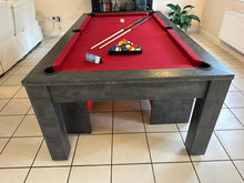Load image into Gallery viewer, Front view of pool dining table with red felt and cue sticks on top.