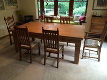 Load image into Gallery viewer, Oak dining table surrounded by traditional wooden chairs.