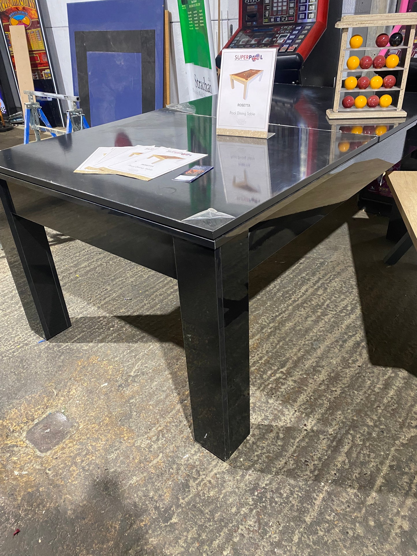 Gloss black Rosetta pool dining table displayed in a showroom with accessories.