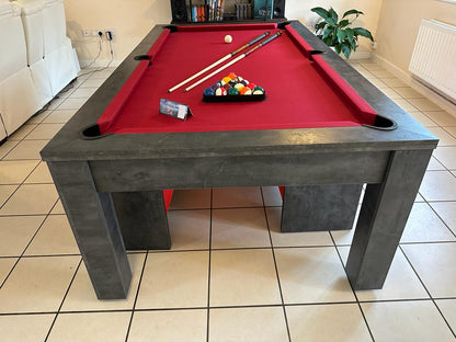 Front view of pool dining table with red felt and cue sticks on top.