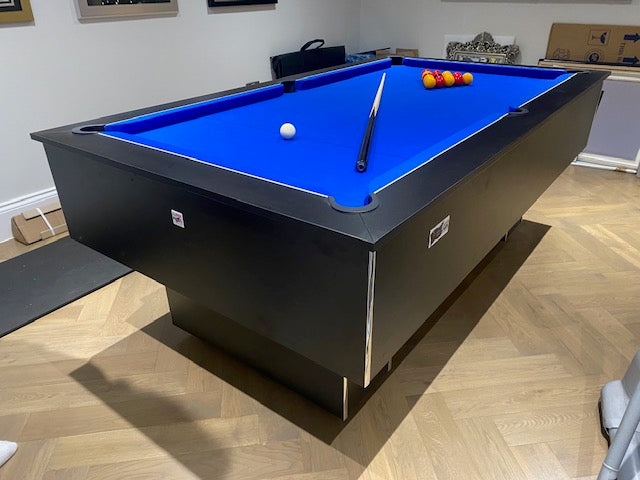 Superpool Black Pearl pool table with blue felt and accessories in a modern room.