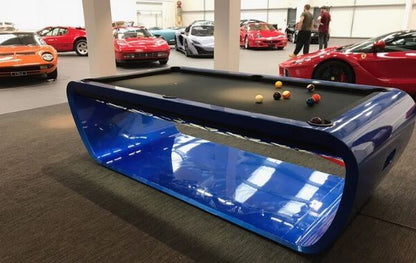 Sleek Blacklight pool table with glossy blue curved frame in luxury setting.