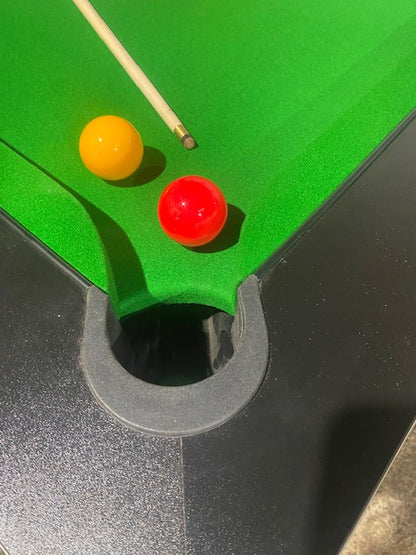 Close-up of Superpool Black Pearl pool table pocket with green felt and balls.