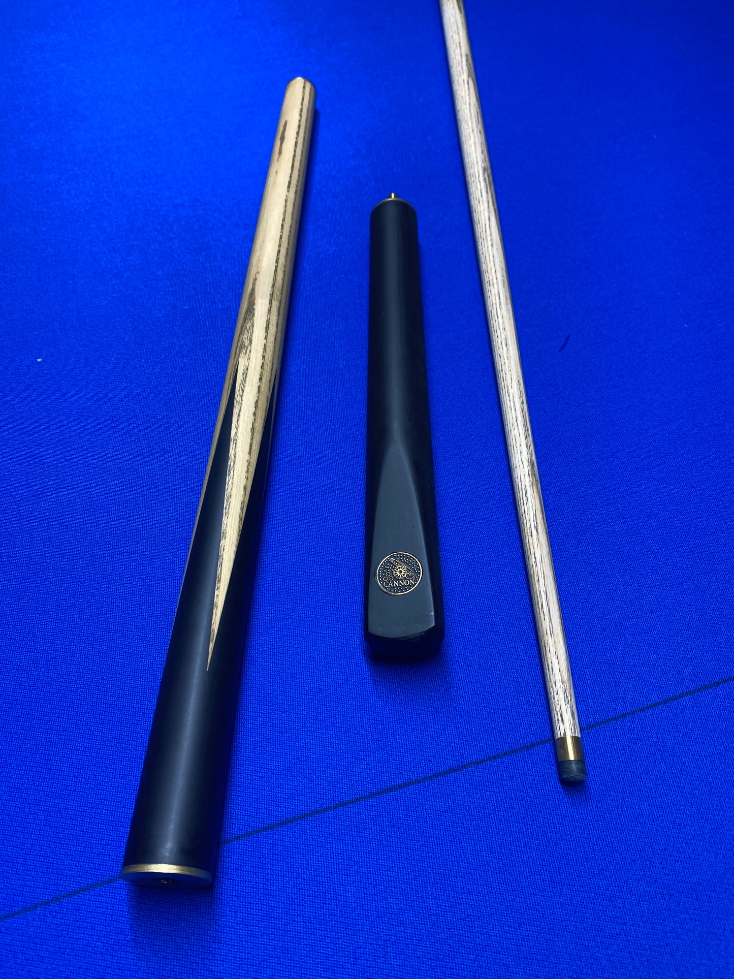 Disassembled Cannon Manta 3 Piece 57-inch cue showing three parts on a blue surface.
