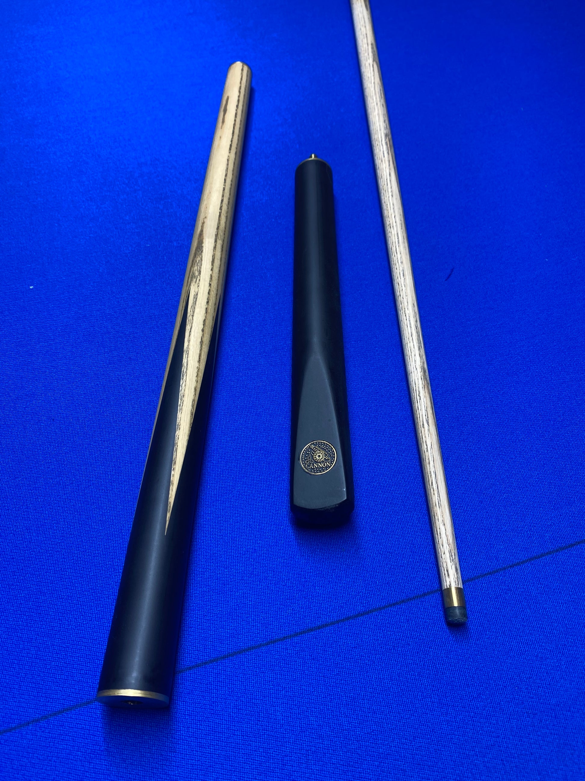 Disassembled Cannon Manta 3 Piece 57-inch cue showing three parts on a blue surface.