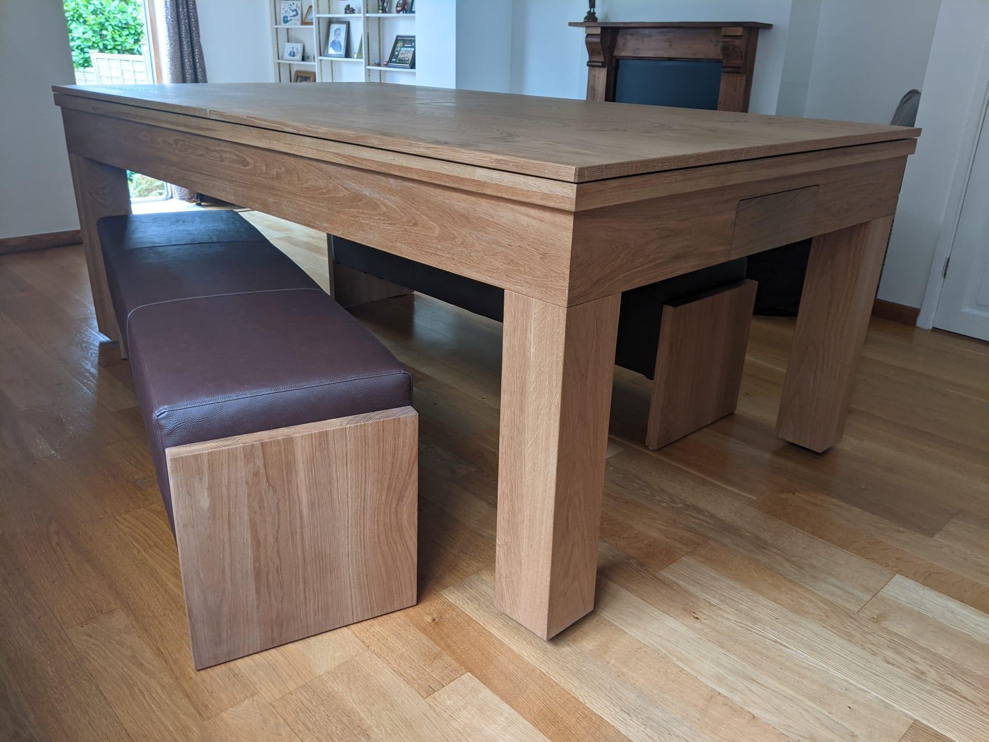 Oak dining pool table with benches in a modern living space.