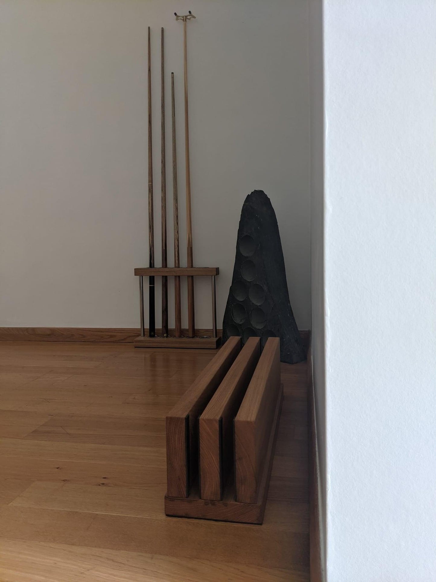 Pool cue rack and accessories placed against a wooden floor.
