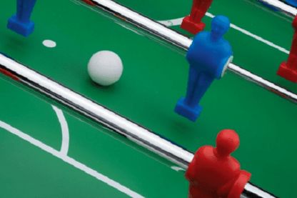 Close-up of Roberto Sport football table with red and blue players and white ball.