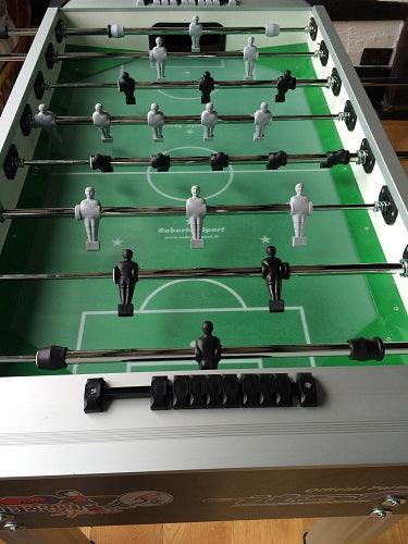 Top view of Roberto Sport football table with black and white players on a green playfield.