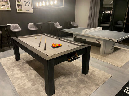Matt Black Rosetta pool dining table in a modern room with a grey surface.