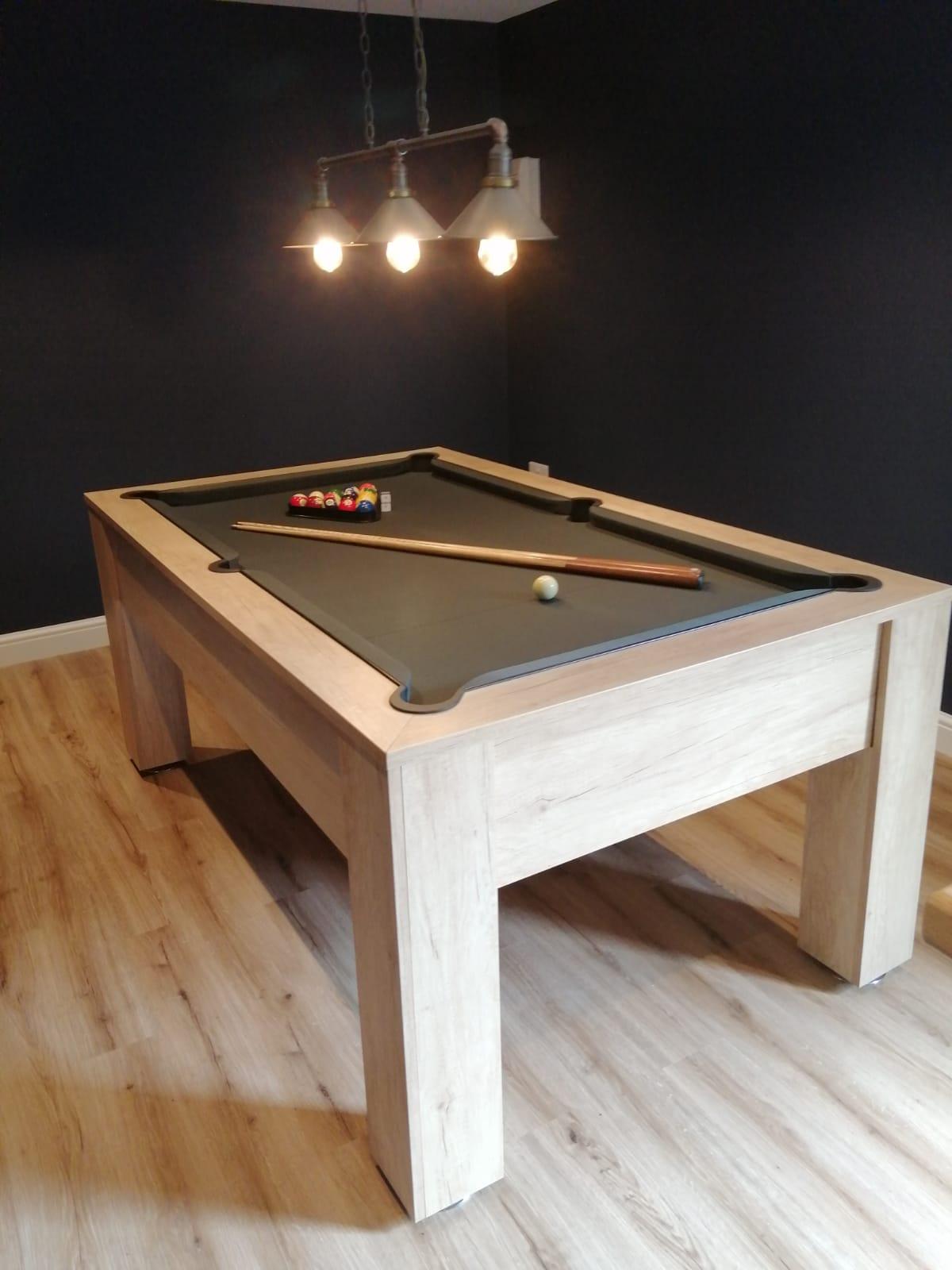 Vintage oak pool table with green felt in a cozy game room setup.