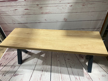 Cross leg pool dining table bench with a natural wood finish and black legs on a rustic floor.