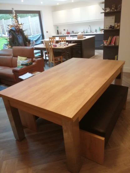 Natural oak dining table with bench seating in a cozy kitchen.