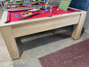 Red felt pool table with oak finish and accessories in a workshop setting.