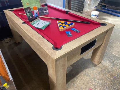 Red felt oak pool table with accessories displayed in a casual setting.