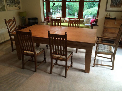 Oak dining table surrounded by traditional wooden chairs.