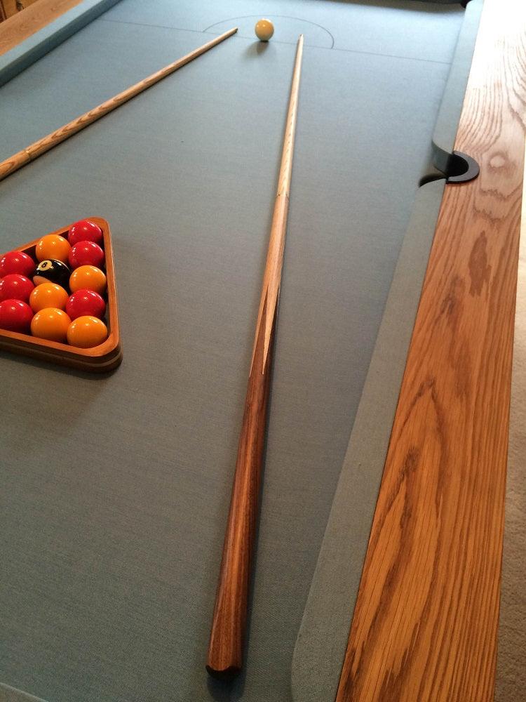 Close-up of oak pool table with blue felt and pool cues.