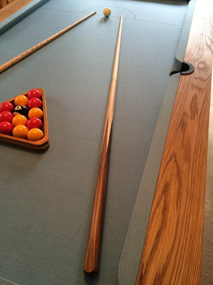 Close-up of oak pool table with blue felt and pool cues.