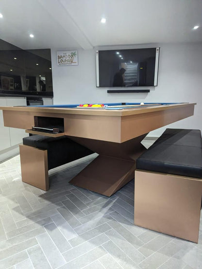 Convertible brushed copper pool table with blue felt and black bench seating.