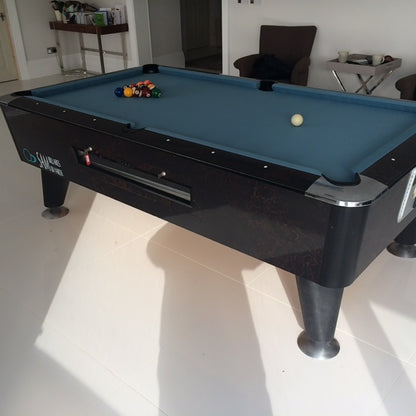 American pool table with blue cloth and sleek black frame in a bright room.