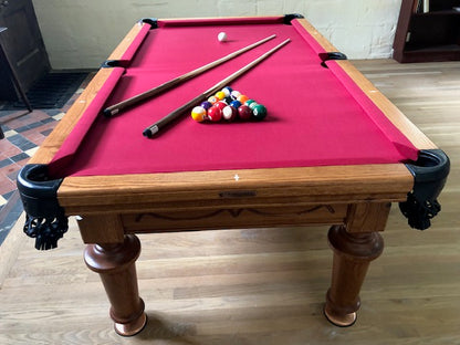 American pool table with red cloth and carved wooden legs in a classic room.