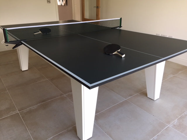 Professional table tennis top with net and paddle on a tiled floor.