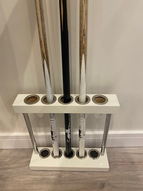 White Superpool Match Cue Stand placed against a wall, holding 5 cues.