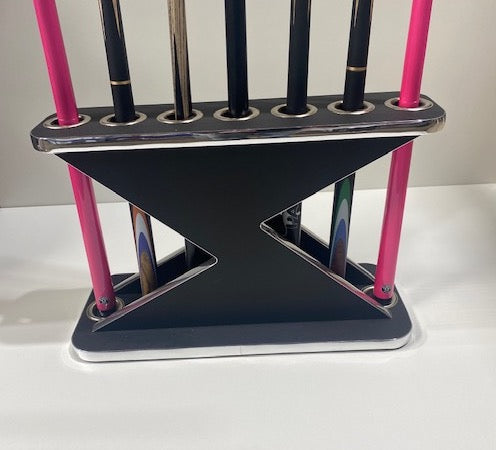 Black and chrome Lightning Cue Stand by Superpool holding pink and black cues.