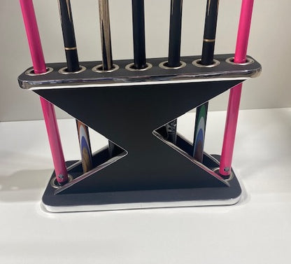 Black and chrome Lightning Cue Stand by Superpool holding pink and black cues.