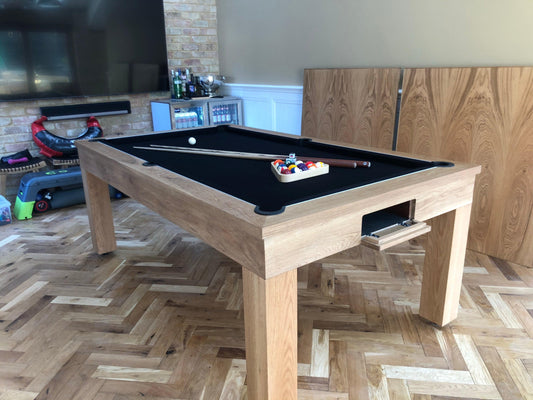 Oak pool table with black felt and pool accessories.